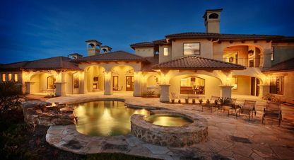 Luxury Mediterranean home with backyard pool at night, typical of Steiner Ranch, West Austin